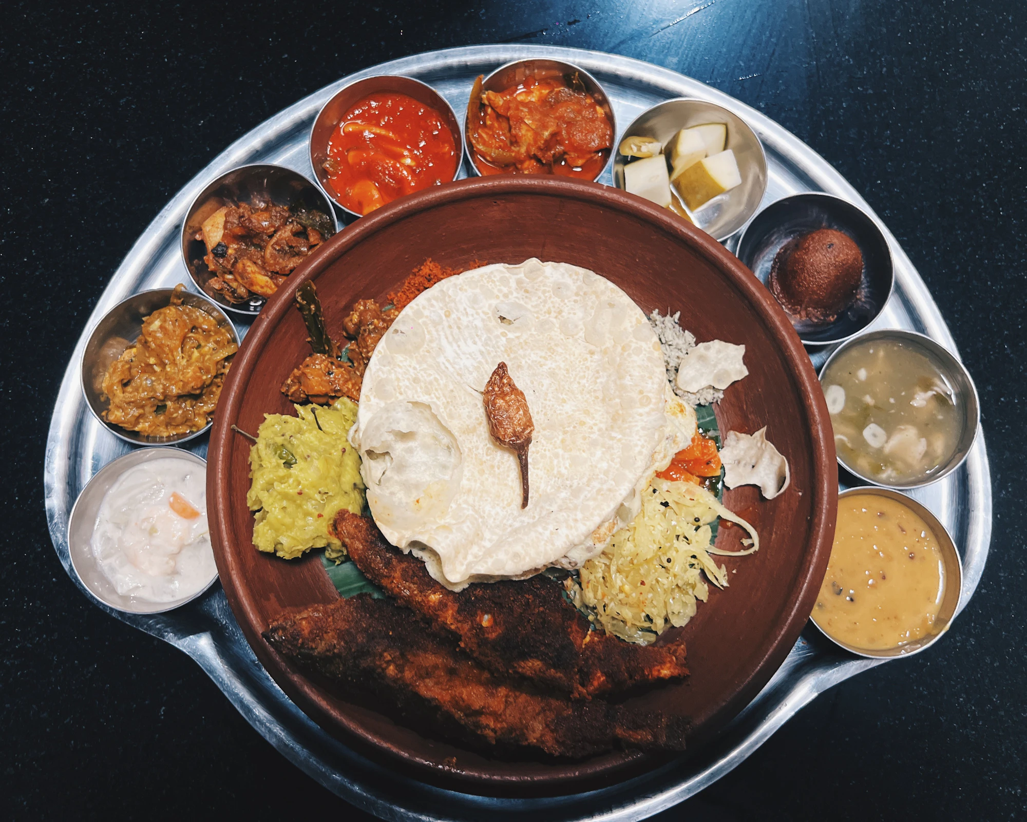 Steel plate with porotta, fish fry and small bowls of Kerala curries
