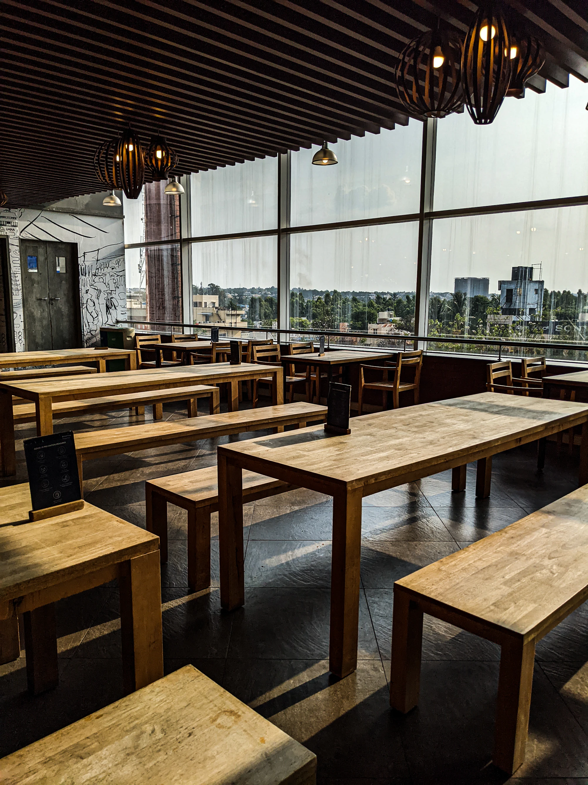 Wooden tables and benches in a bright dining room with large windows