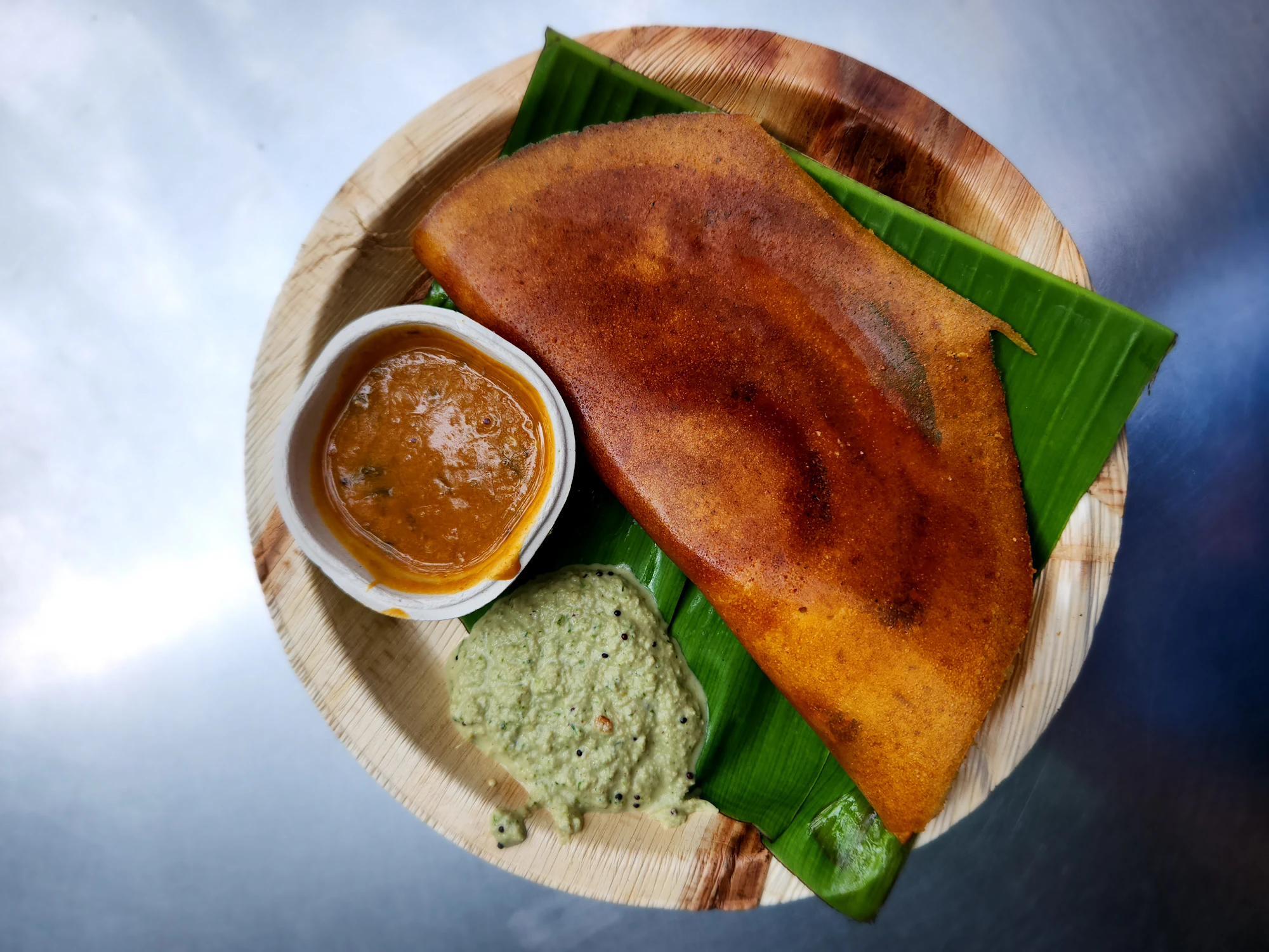 Folded ghee roast dosa with sambar and green chutney on a leaf plate