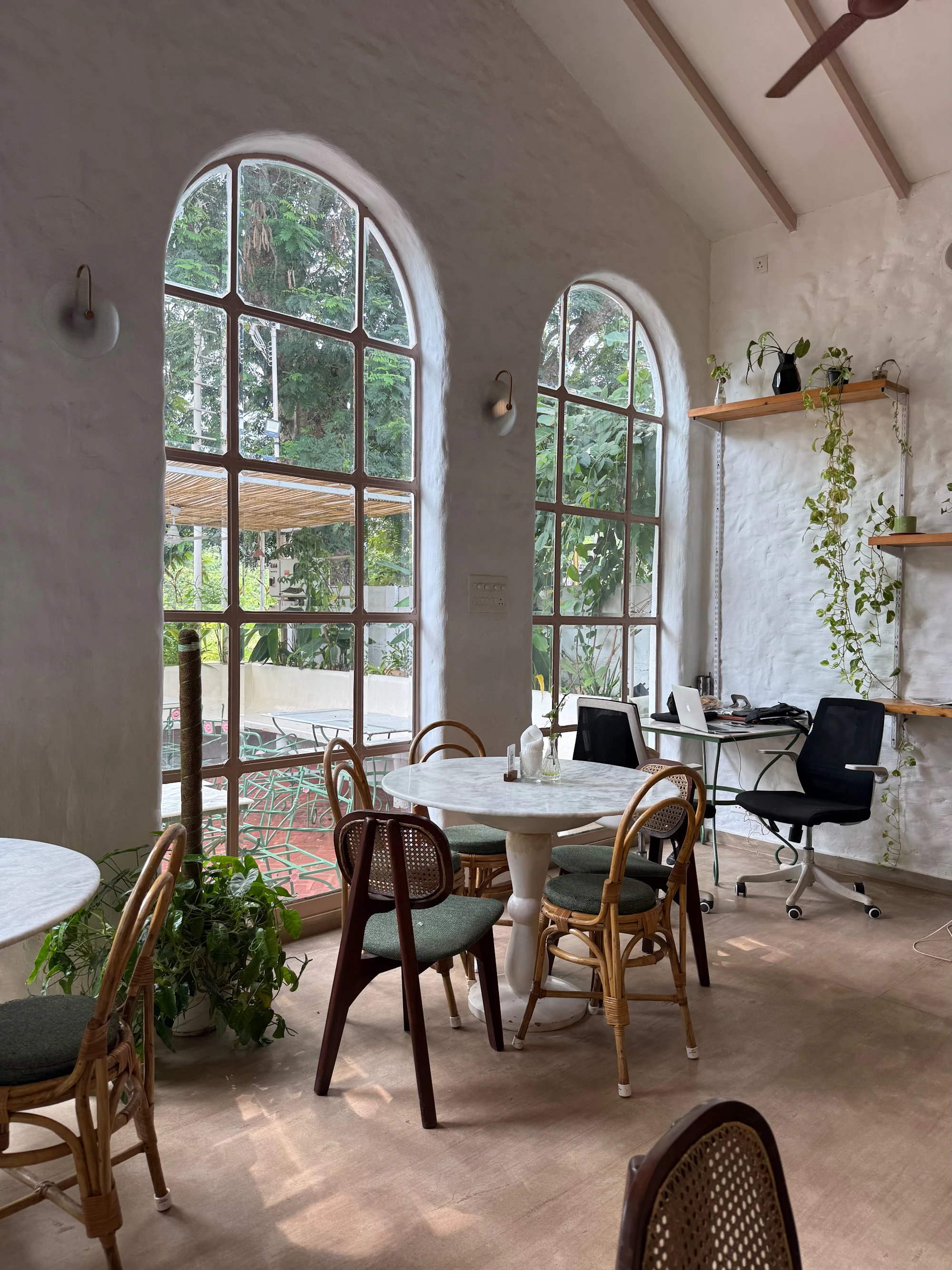 Café corner with round tables, cane chairs and arched windows