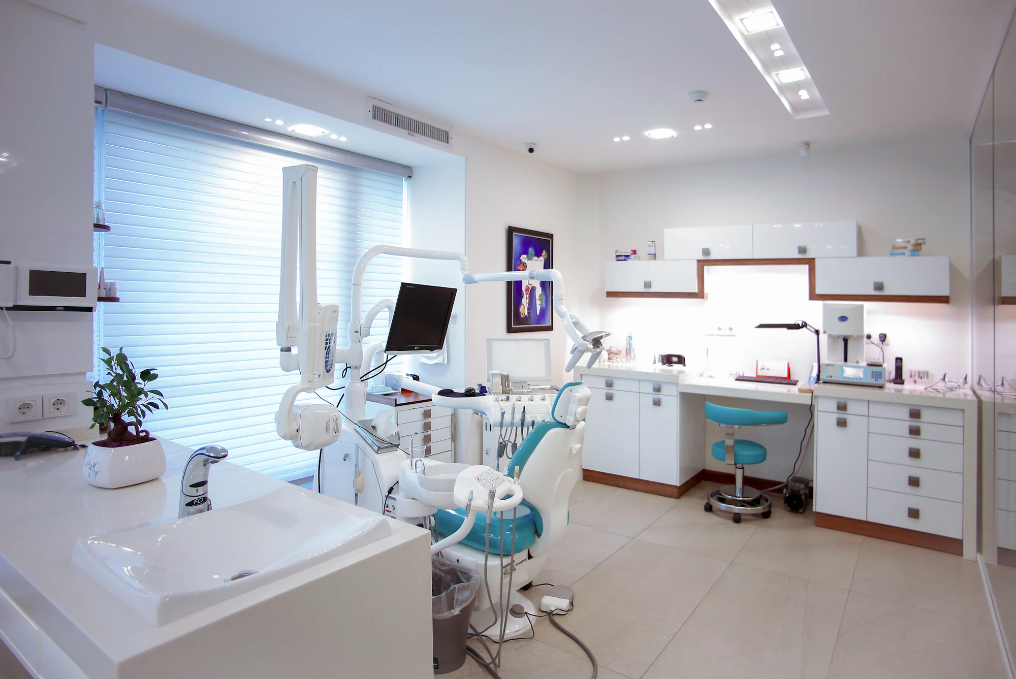 A bright dental surgery with a patient chair, a sink and a window with blinds