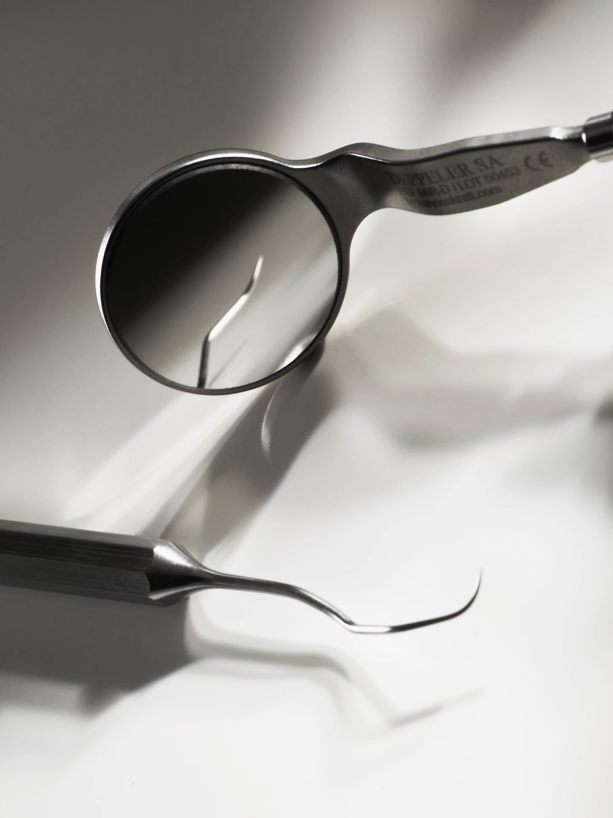 Close-up of a dental mirror and explorer on a white surface