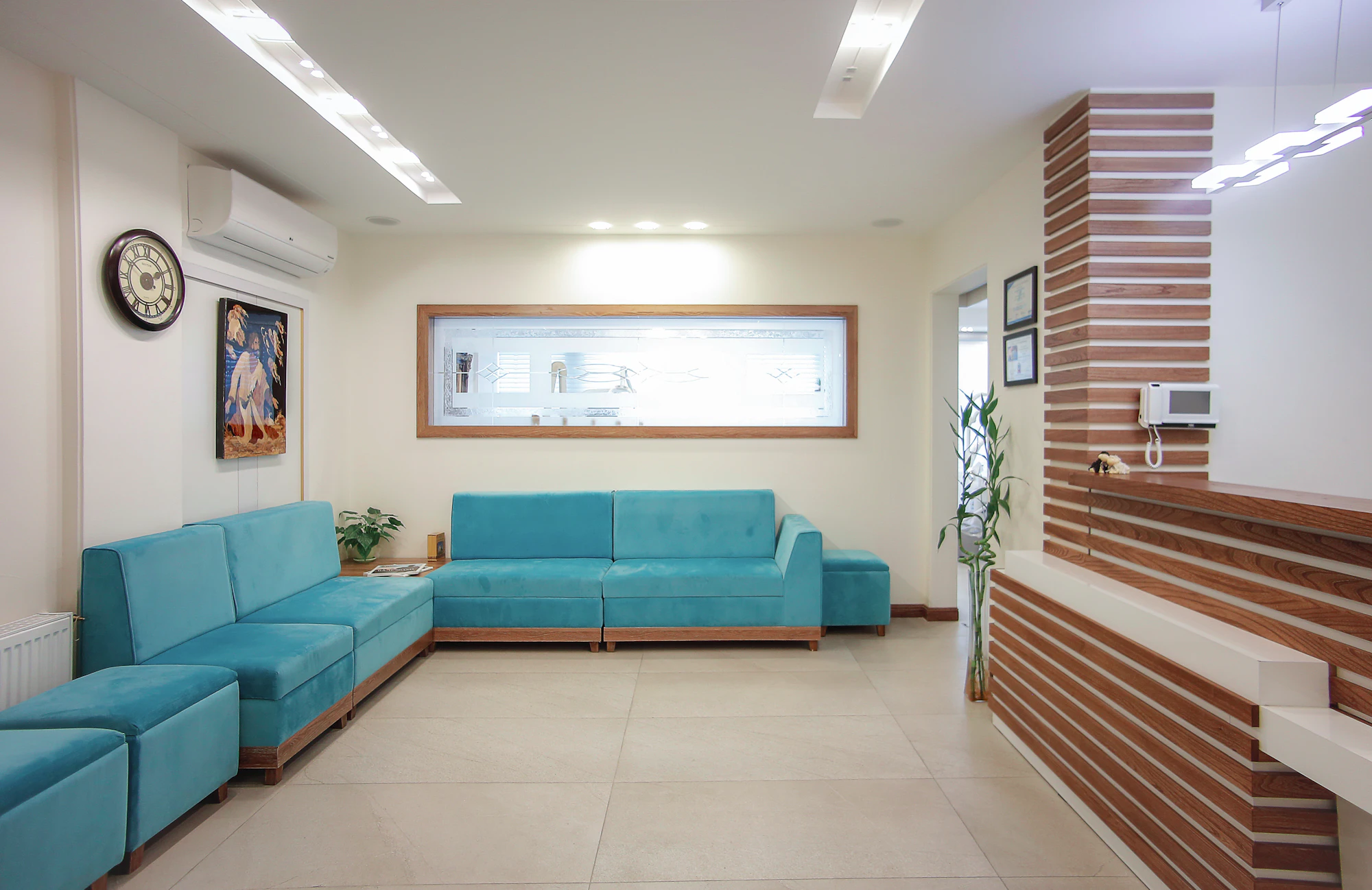 A clinic waiting area with turquoise sofas and a wall clock