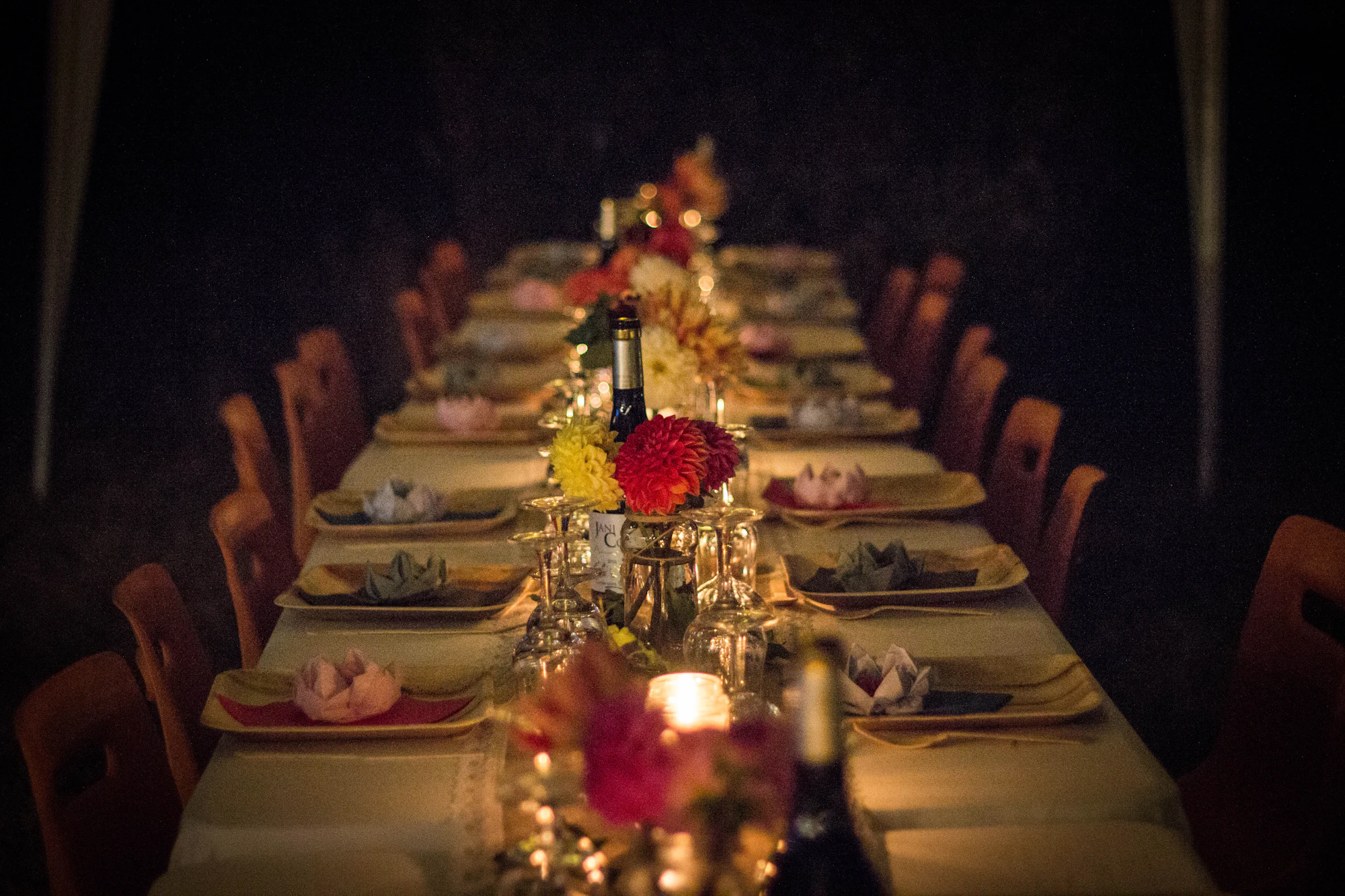 A long candlelit dinner table set with flowers and small lamps