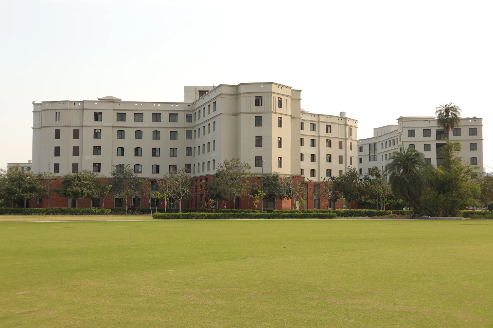 A long cream-coloured school building behind a wide green playing field
