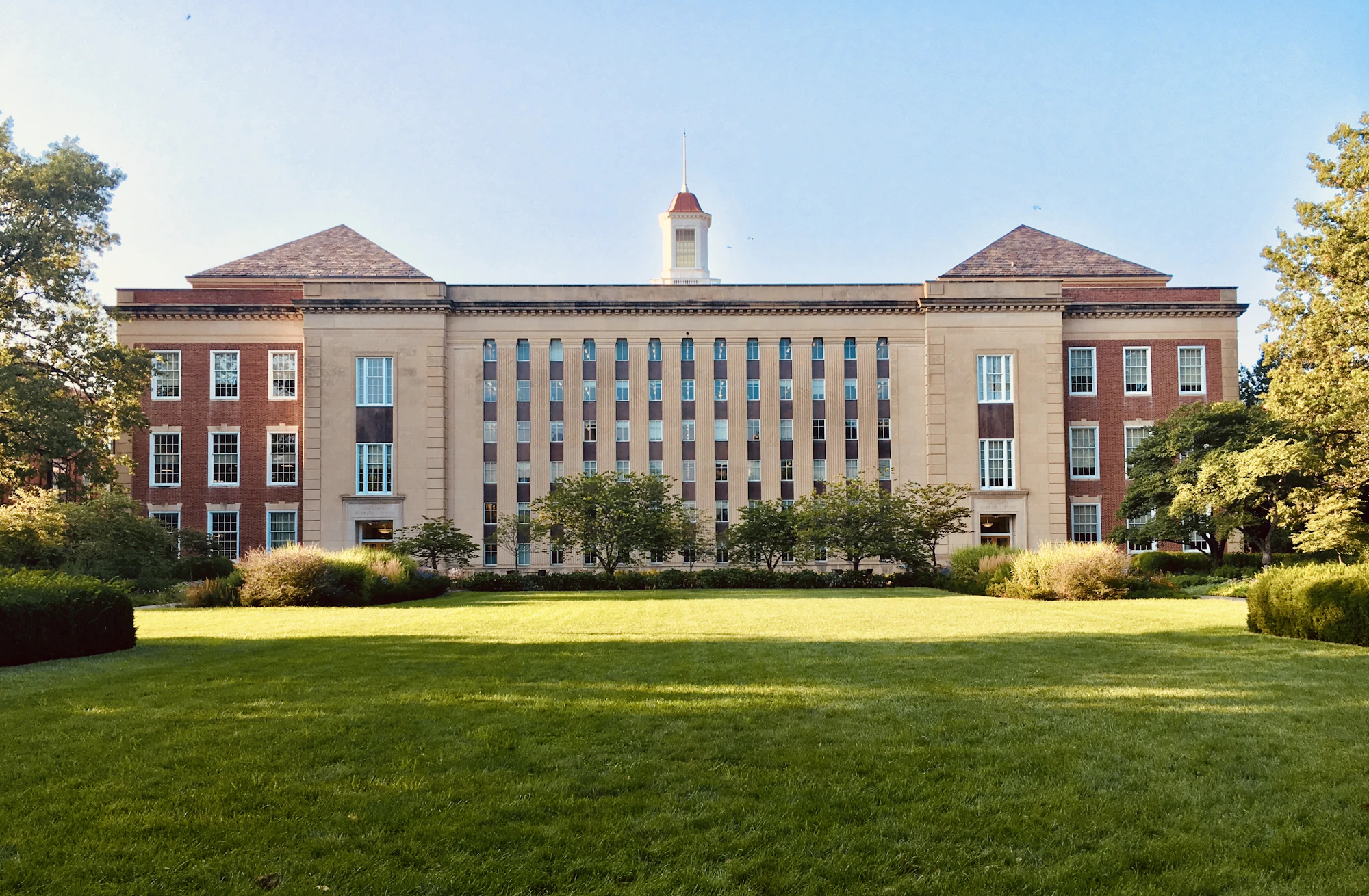 A long college building behind a wide lawn