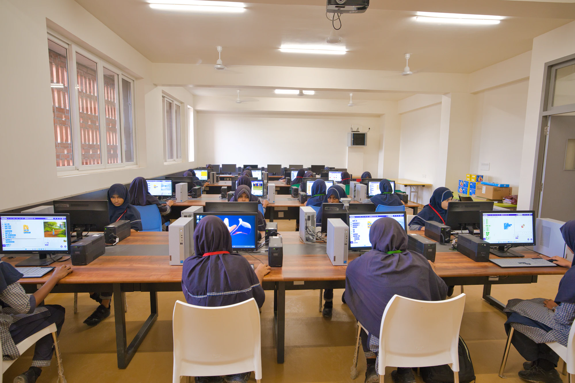 Students working at rows of computers in a bright computer lab