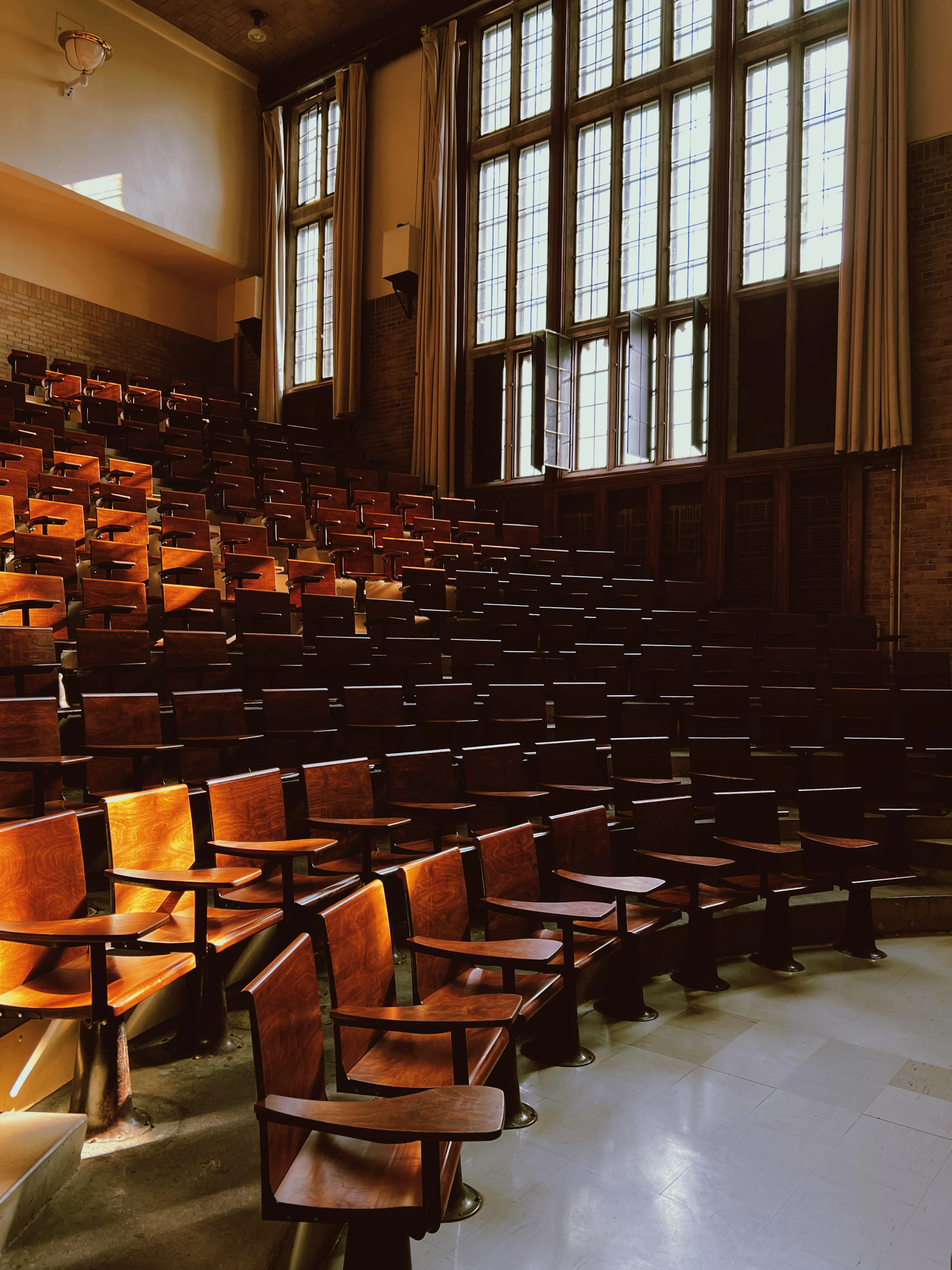 Wooden chairs in an old classroom with tall windows