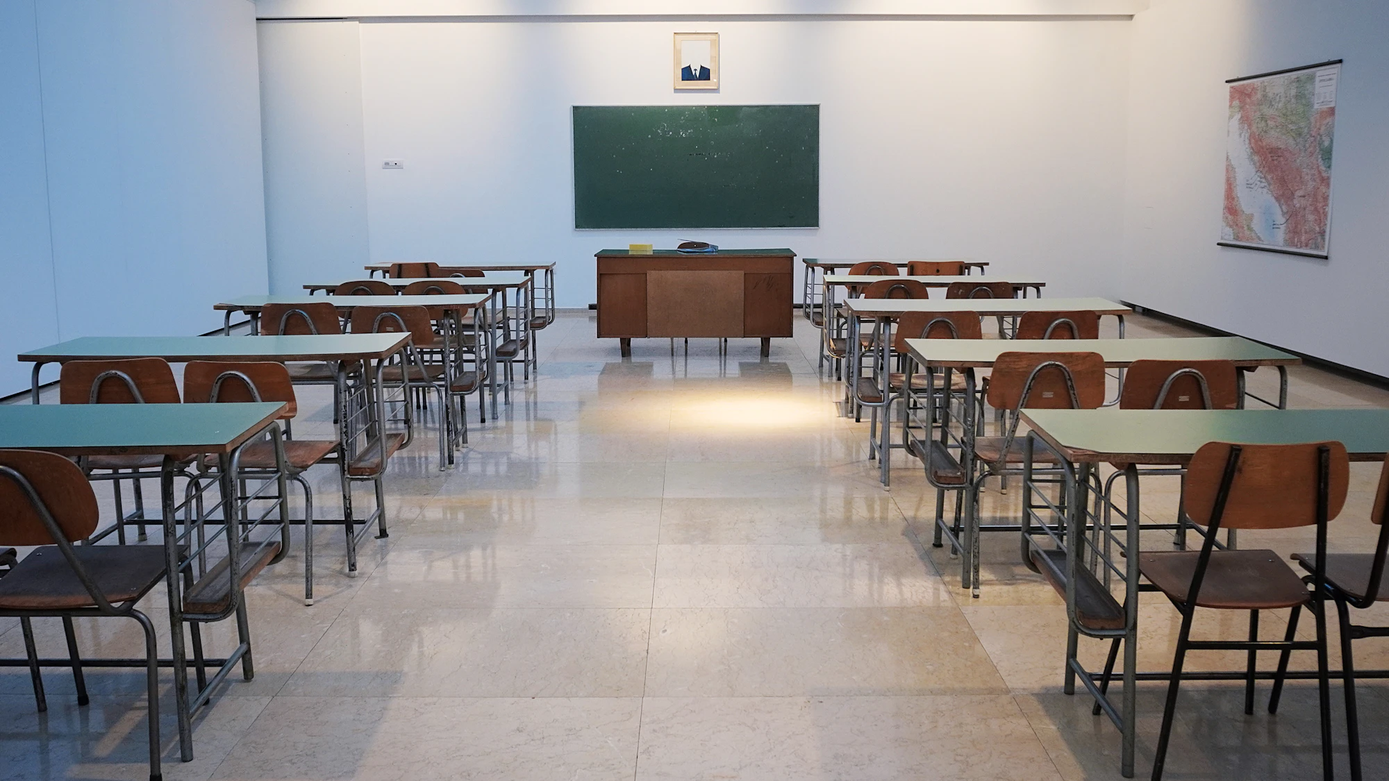 An empty classroom with desks and a blackboard