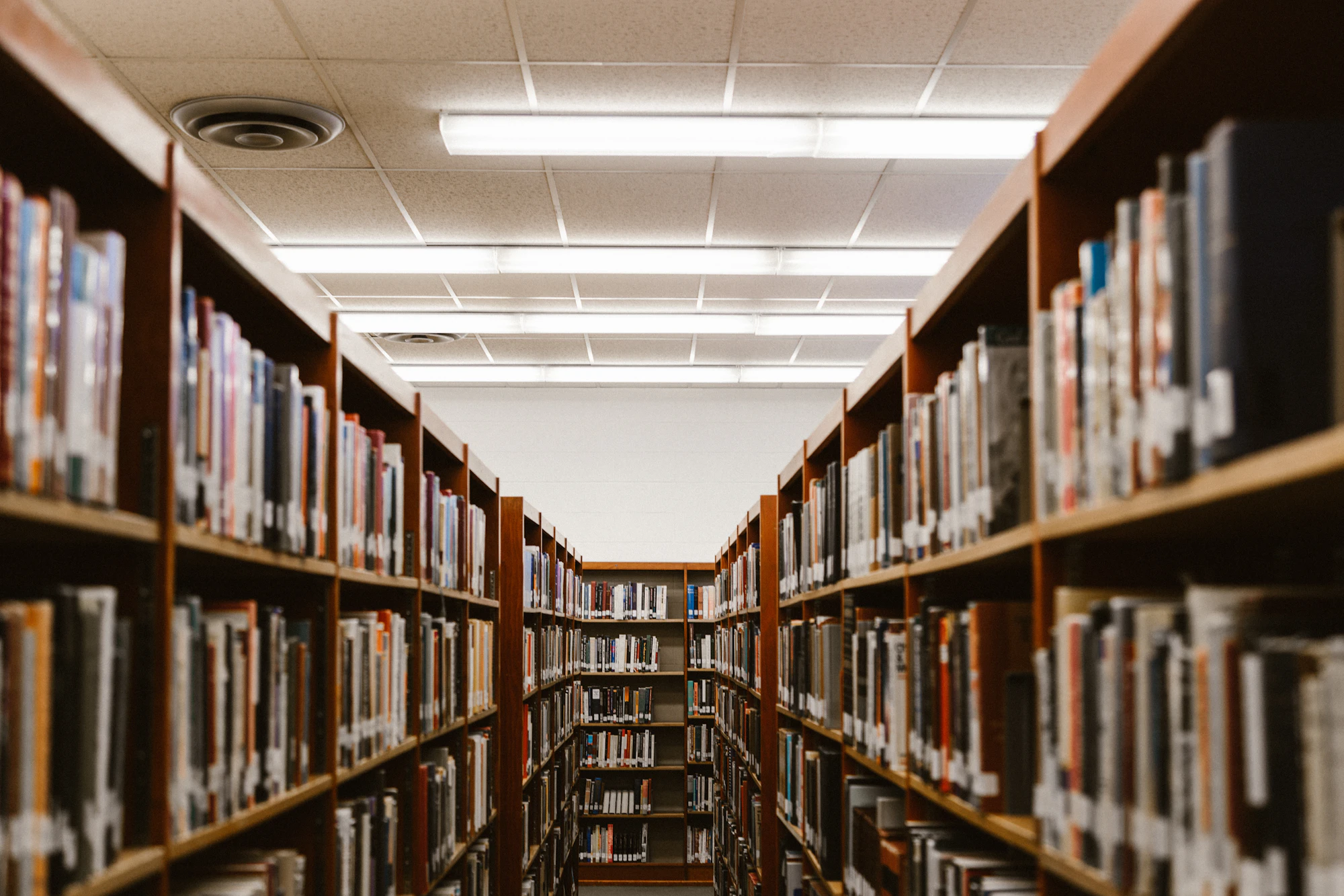 An aisle between tall library bookshelves