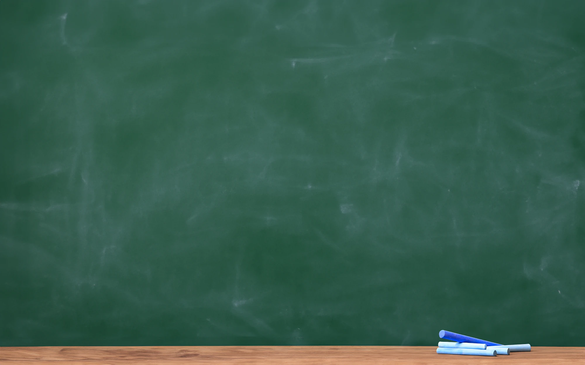 Blue chalk sticks on the ledge of a green chalkboard