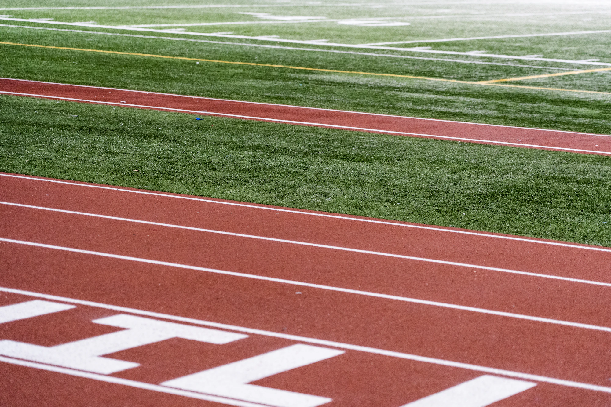 Lanes of a red running track beside a green field