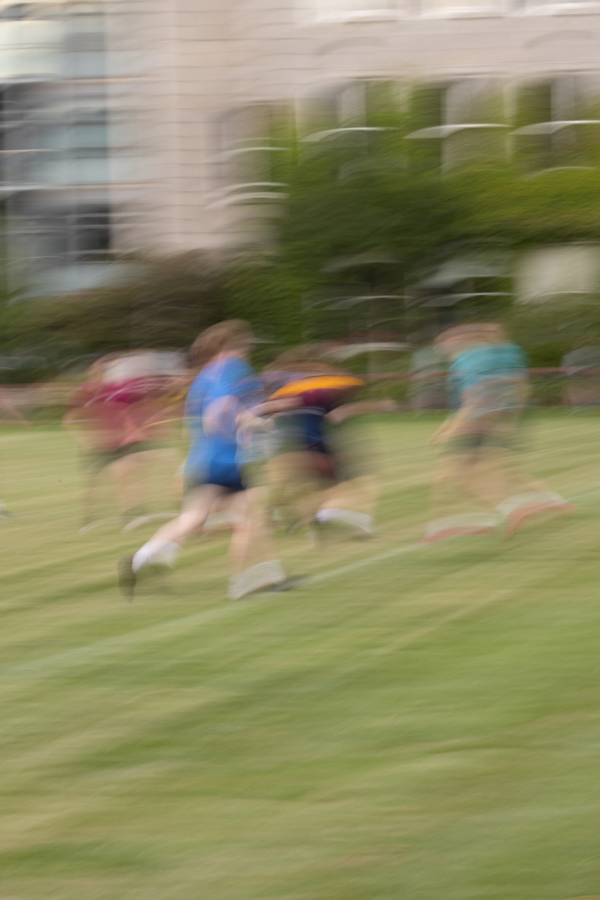 Children running across a green field, blurred with motion