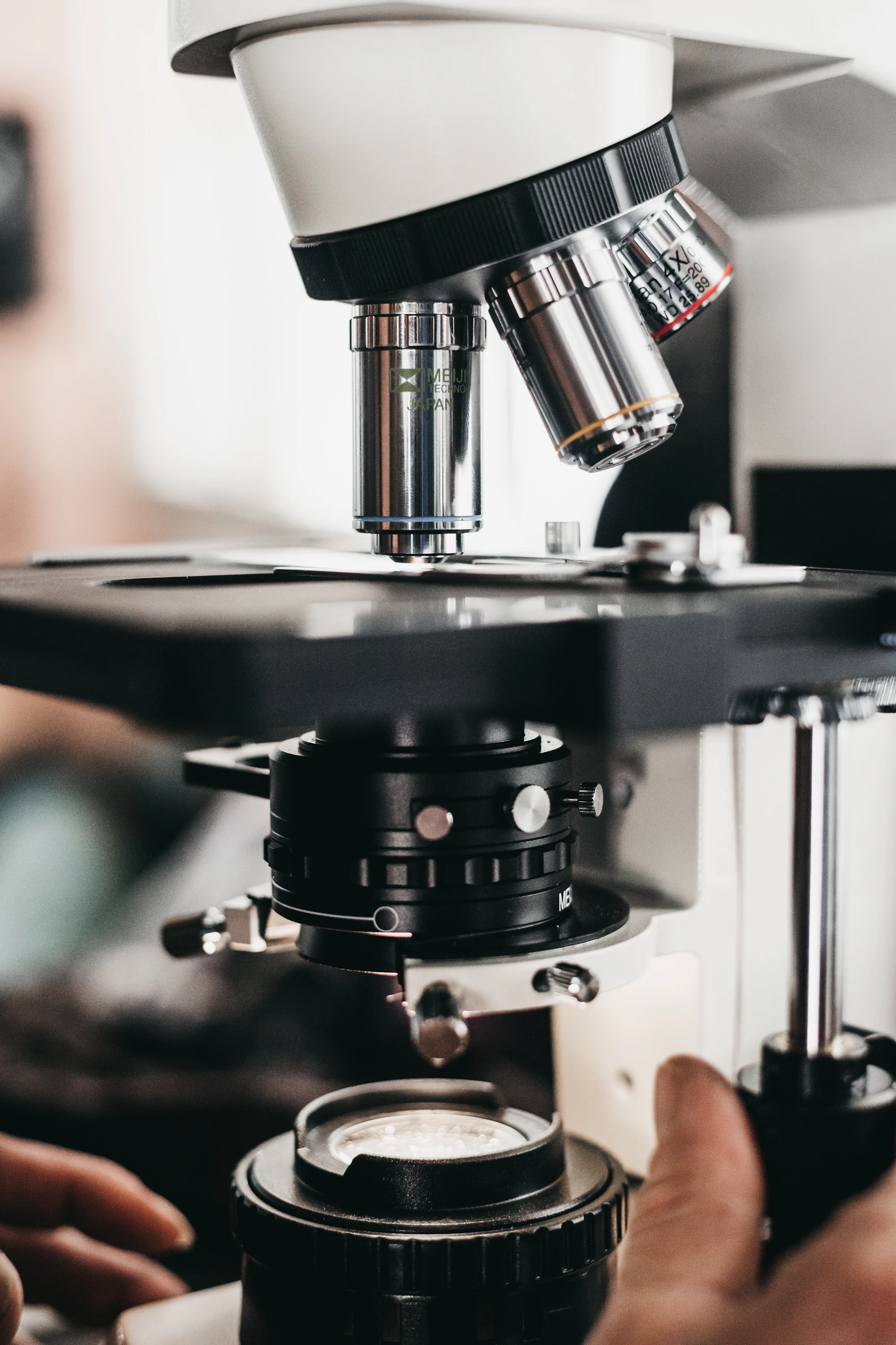 Close-up of hands adjusting a microscope