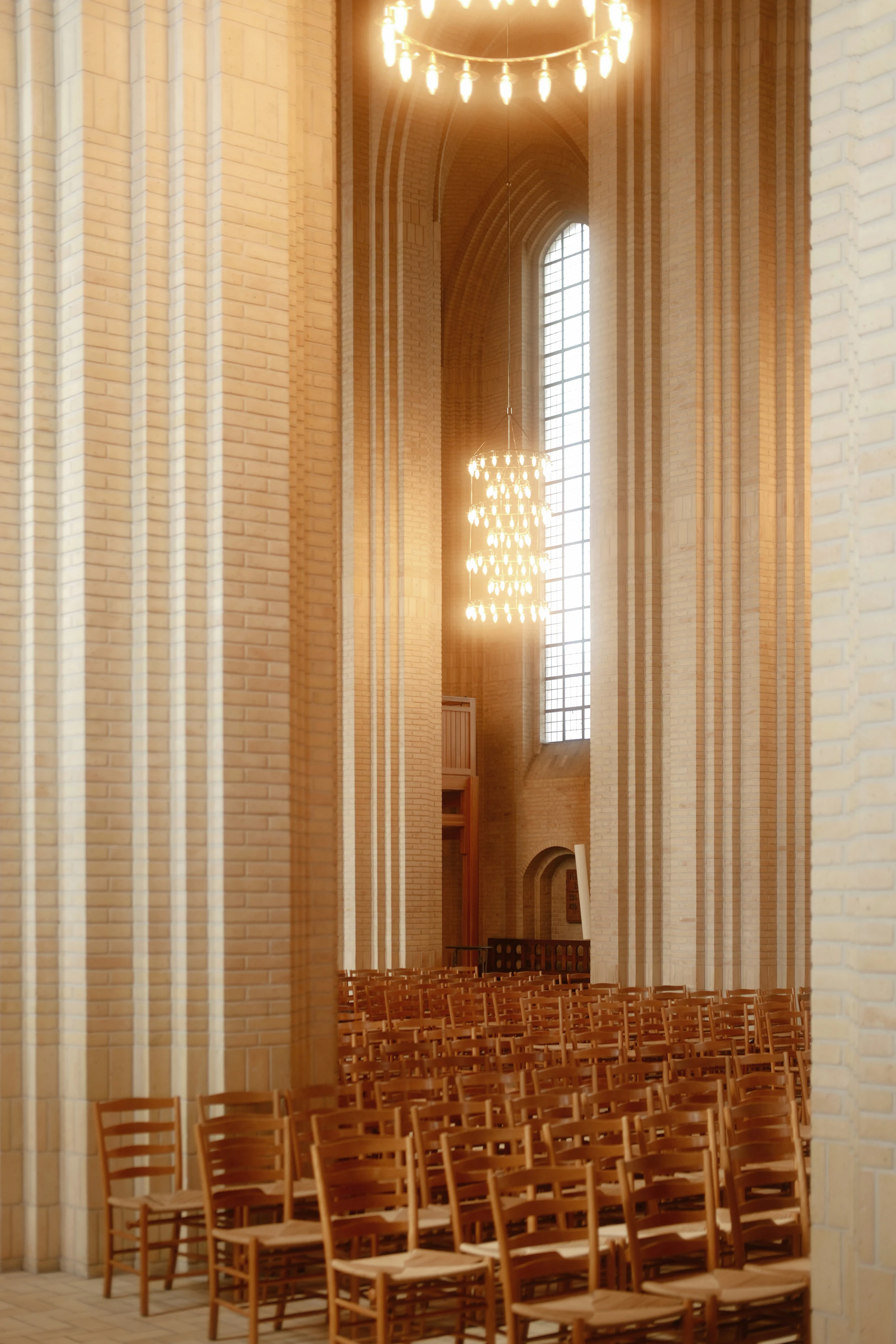Rows of wooden chairs inside a tall, light-filled church interior