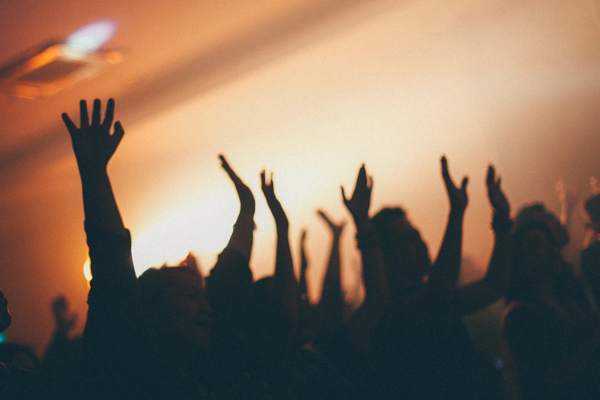 Silhouettes of raised hands against warm light