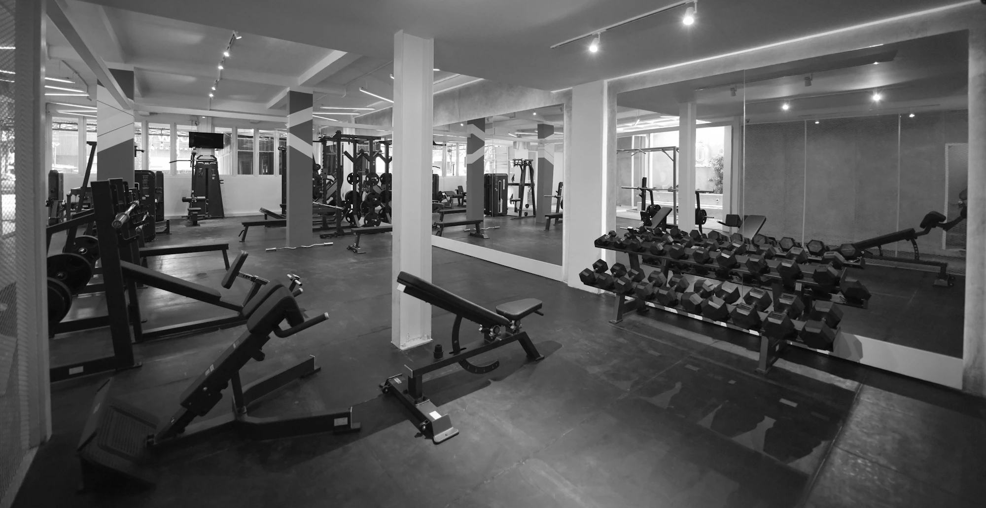 Benches and dumbbell racks in a mirrored weights room