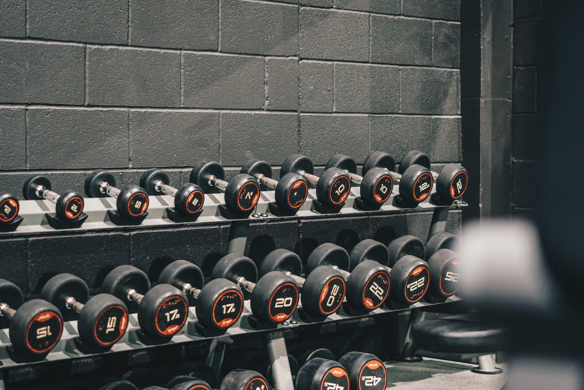 Rows of dumbbells on a rack against a block wall