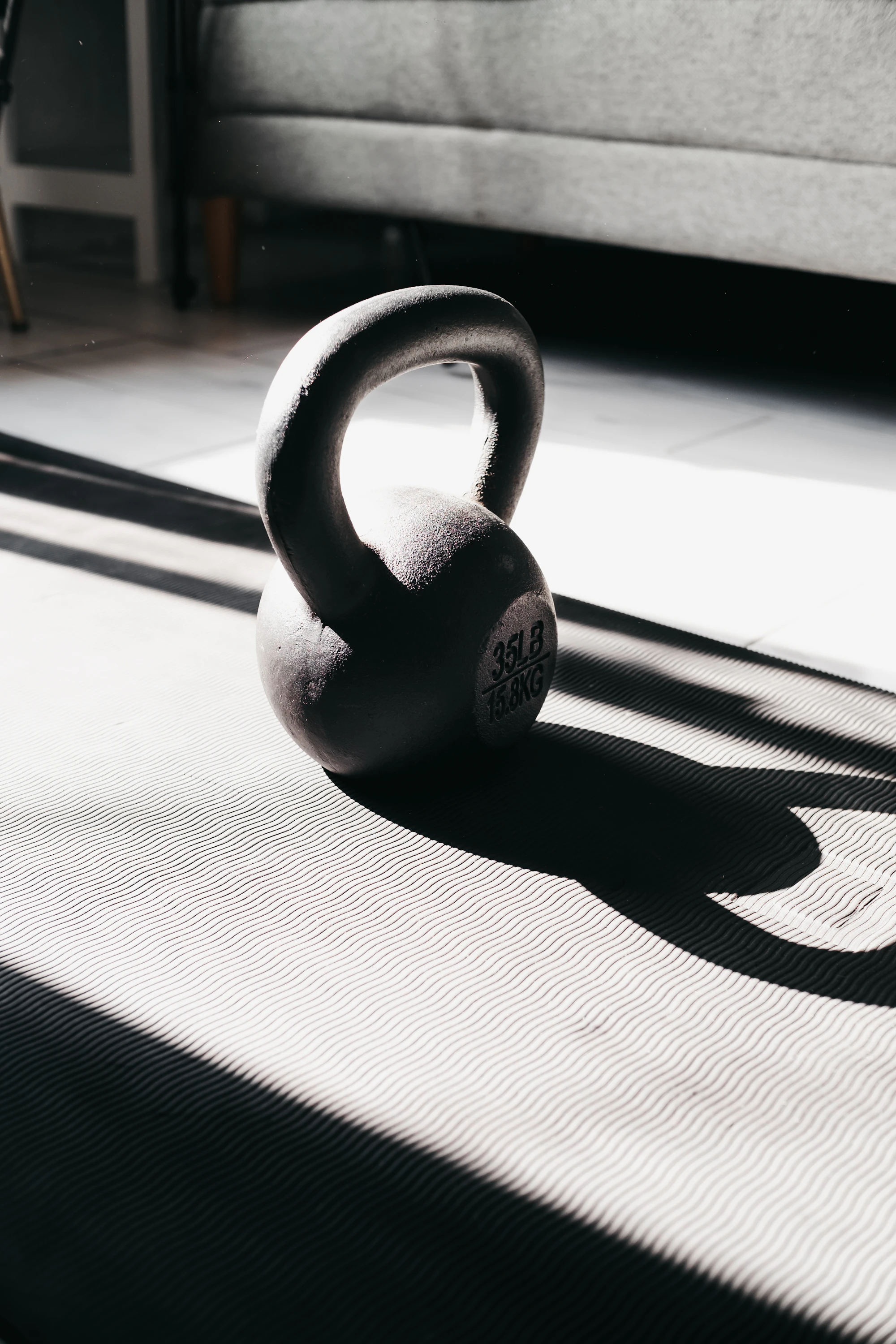 A kettlebell on a mat in a patch of sunlight