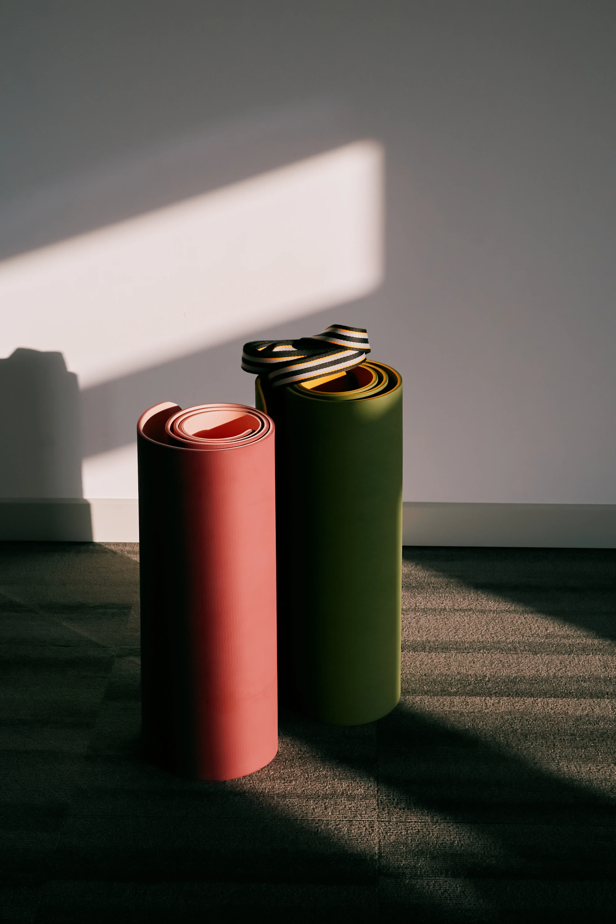 Two rolled yoga mats standing against a wall