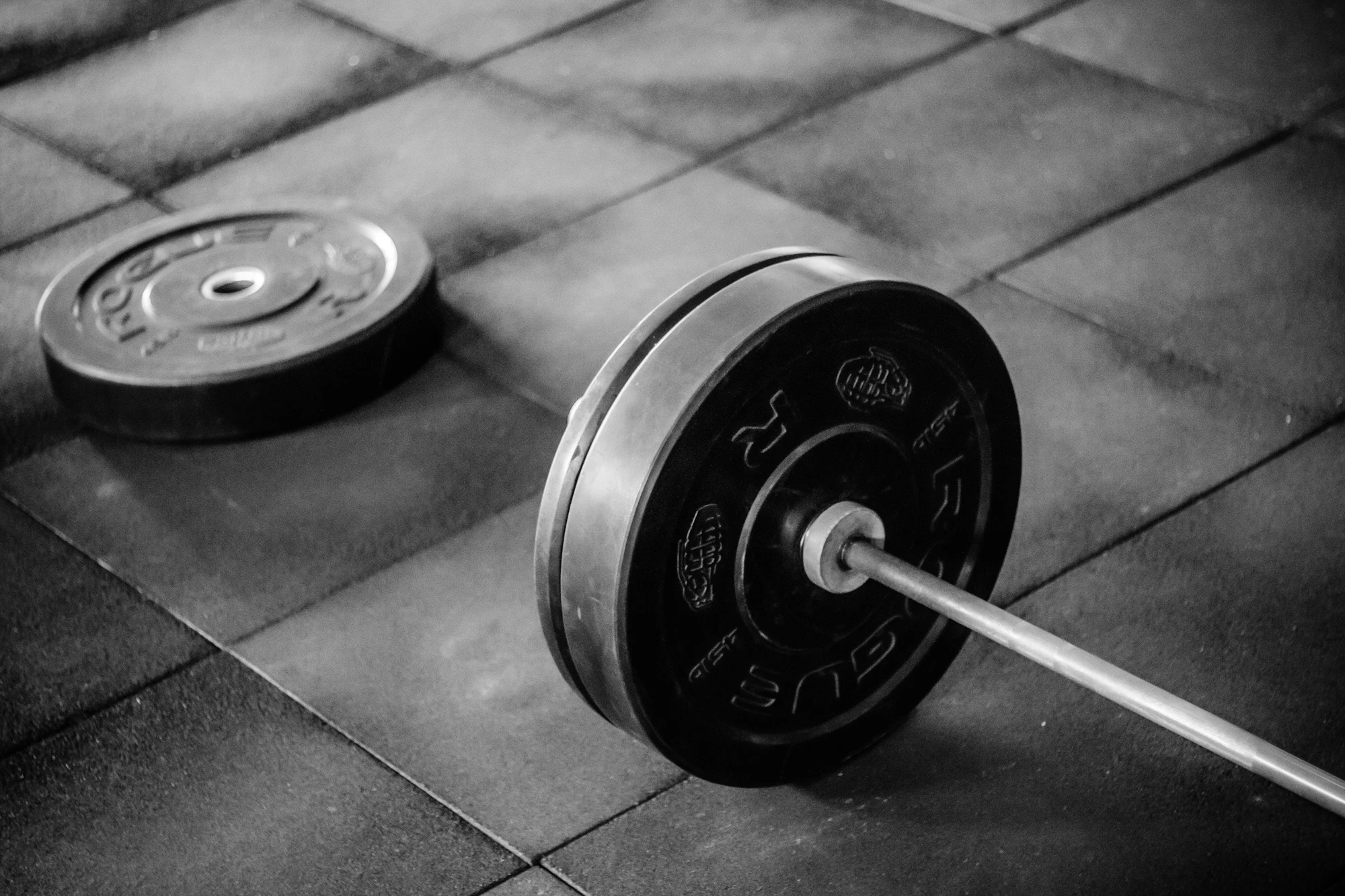 A barbell with plates on rubber floor tiles