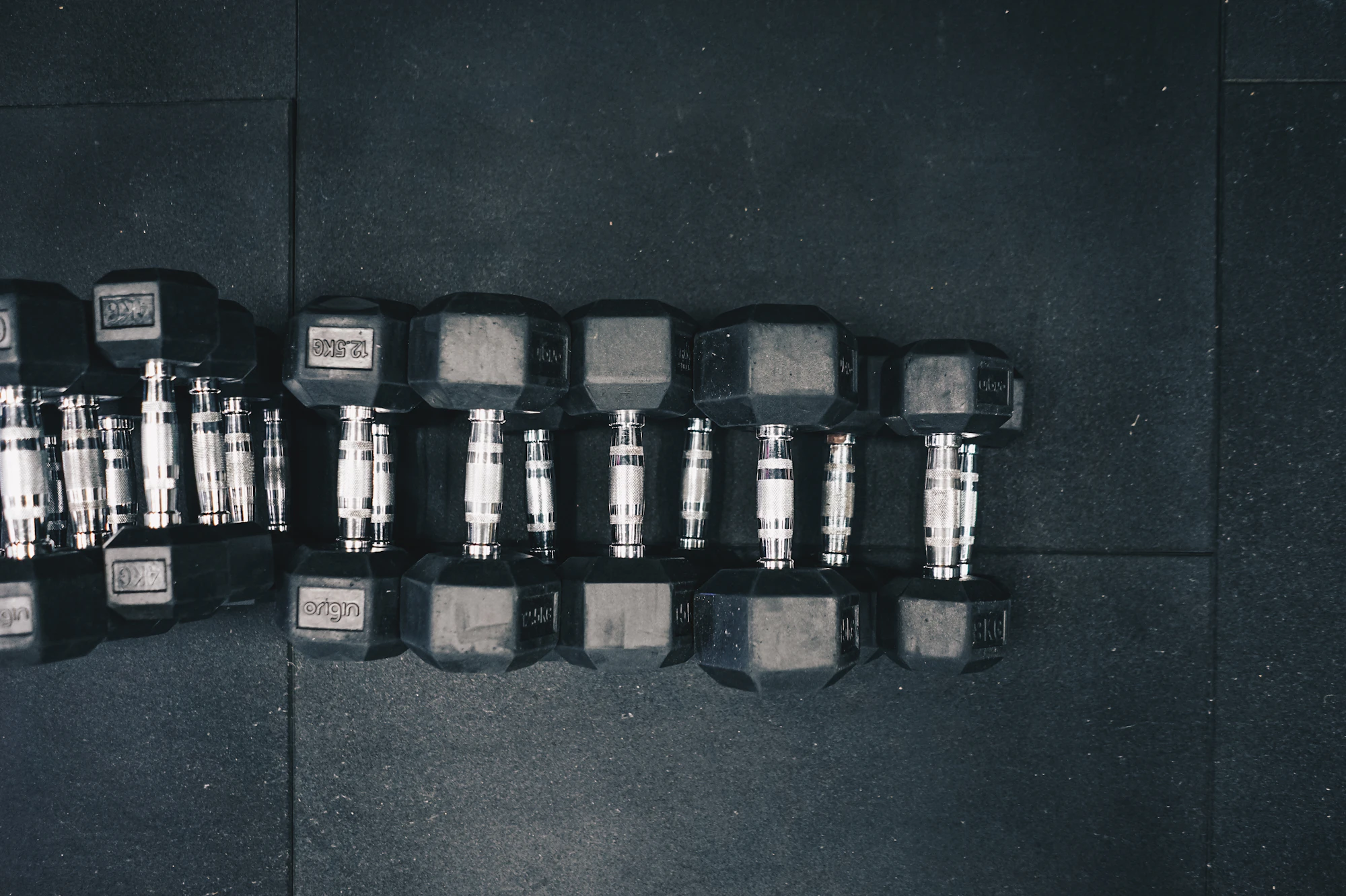 A row of hex dumbbells on a dark floor, from above