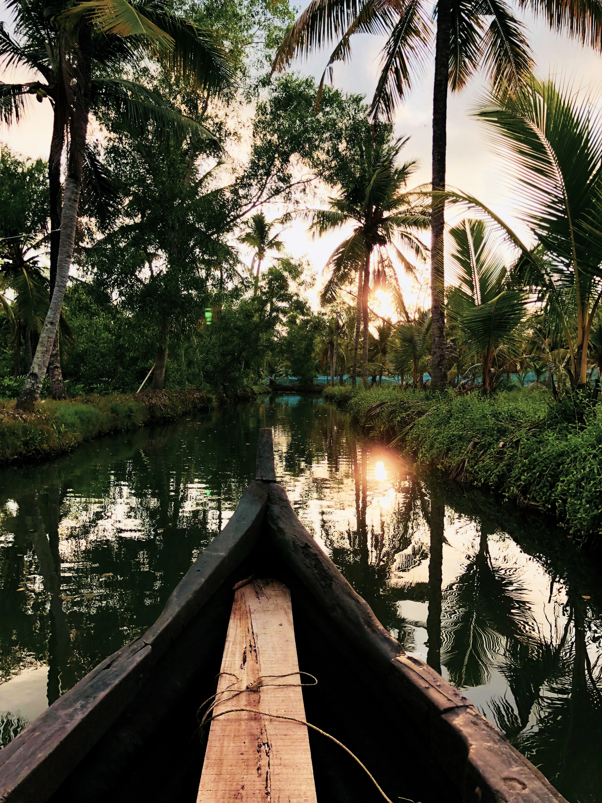 The bow of a wooden canoe on a quiet canal at sunrise