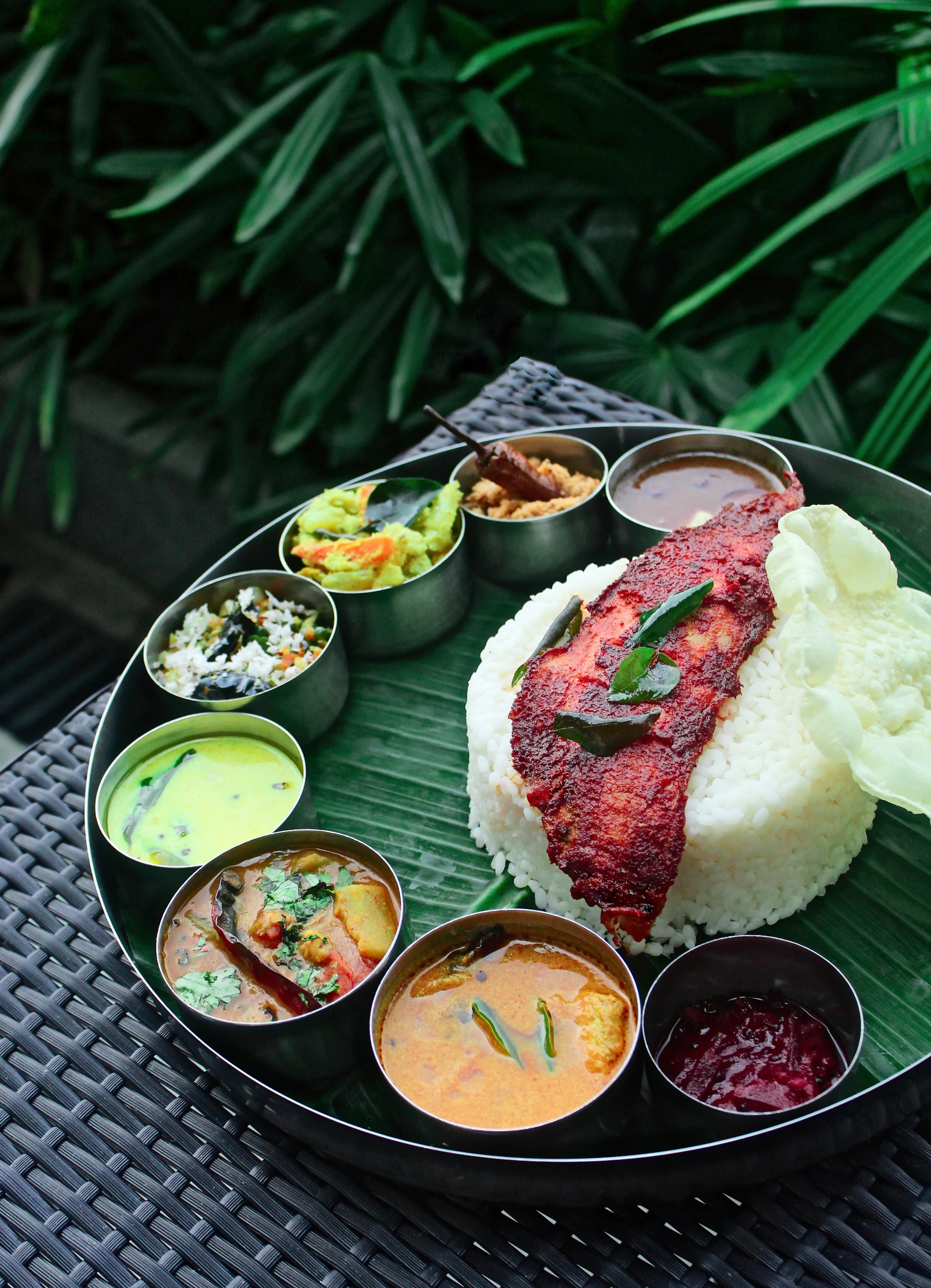 Fried fish, rice and curries on a banana leaf outdoors
