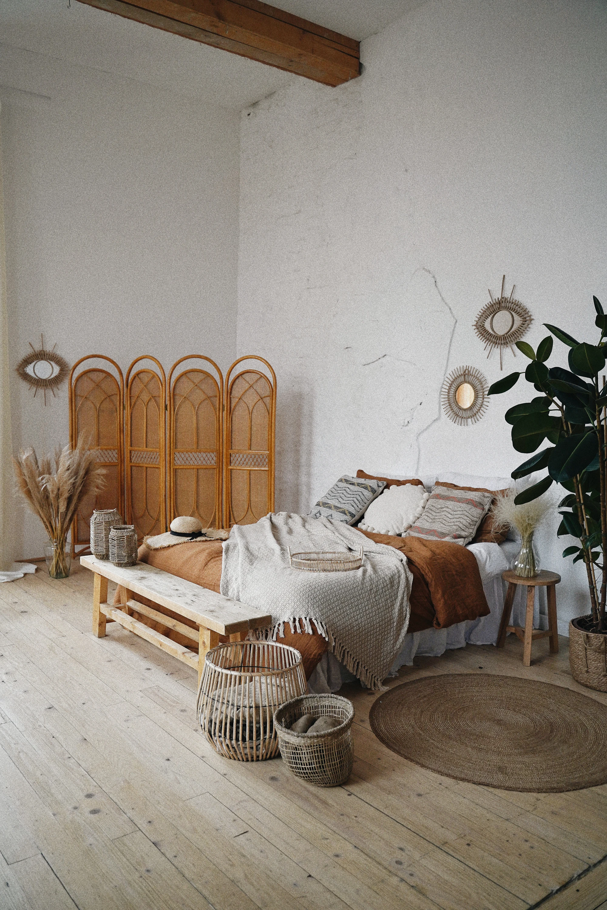 A bright room with a bed, cane furniture and a wooden screen