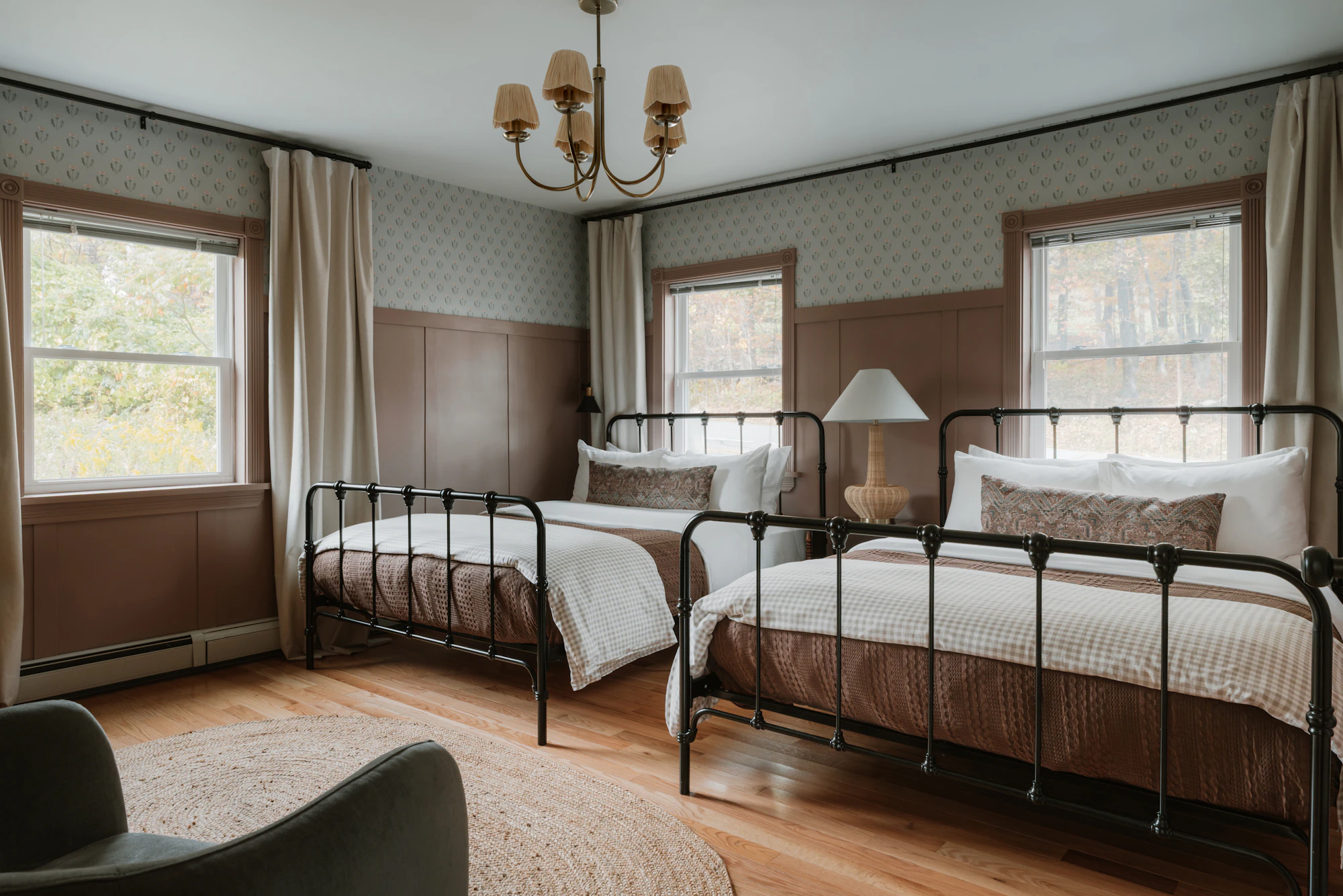 Two iron-framed beds in a room with tall windows