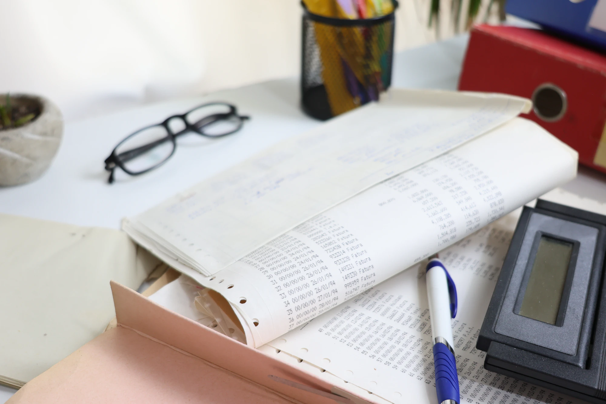 Desk with an open ledger, glasses, a pen and a calculator