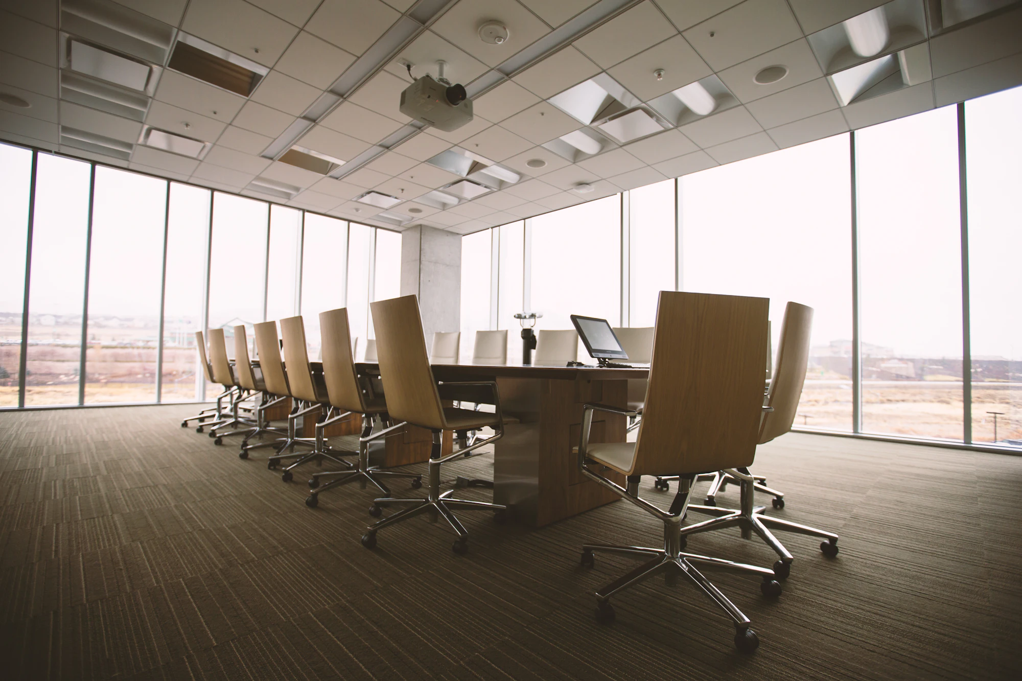 Conference room with a long table and leather chairs by tall windows