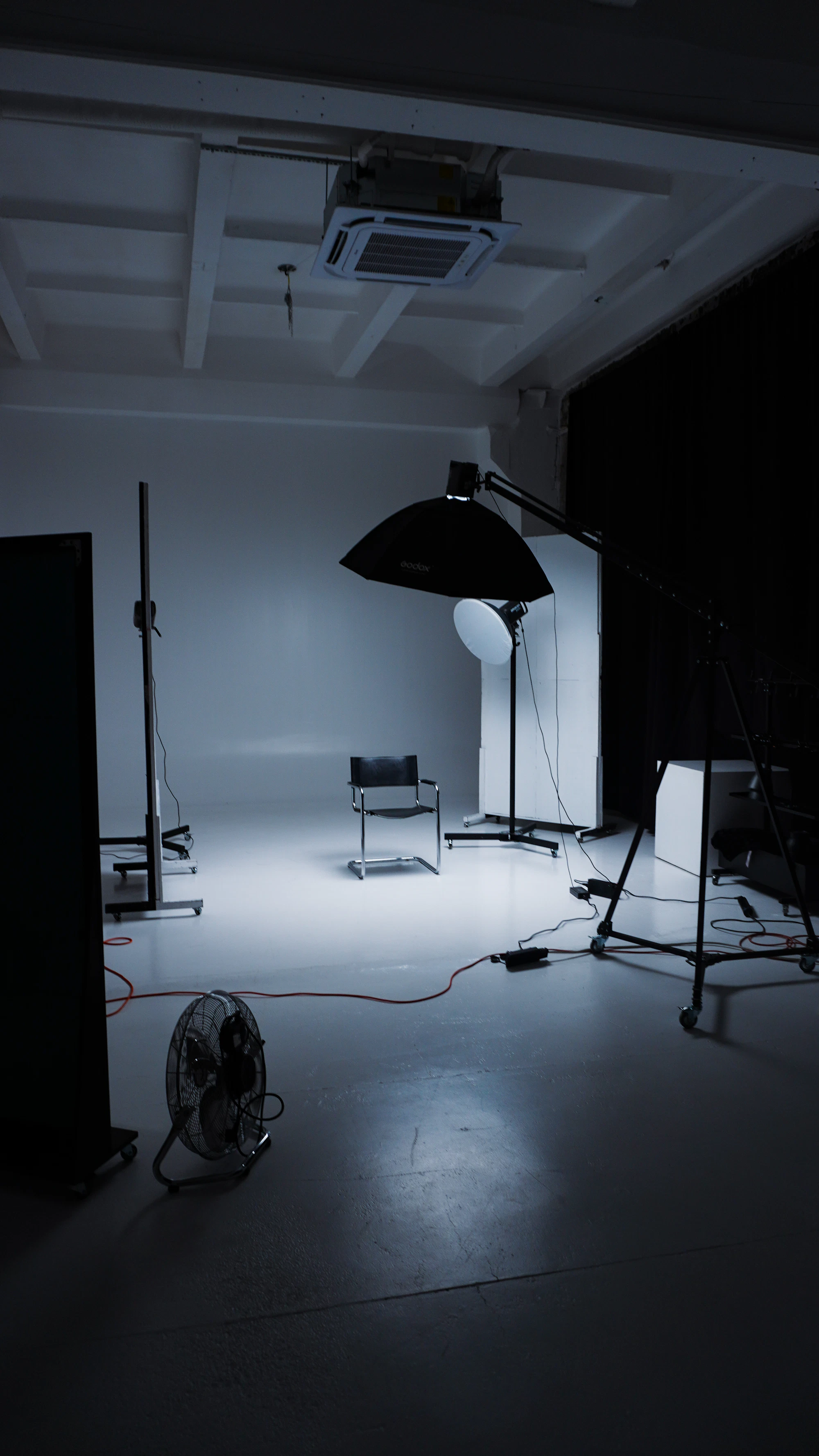 Empty photo studio with a white floor, softbox and stands