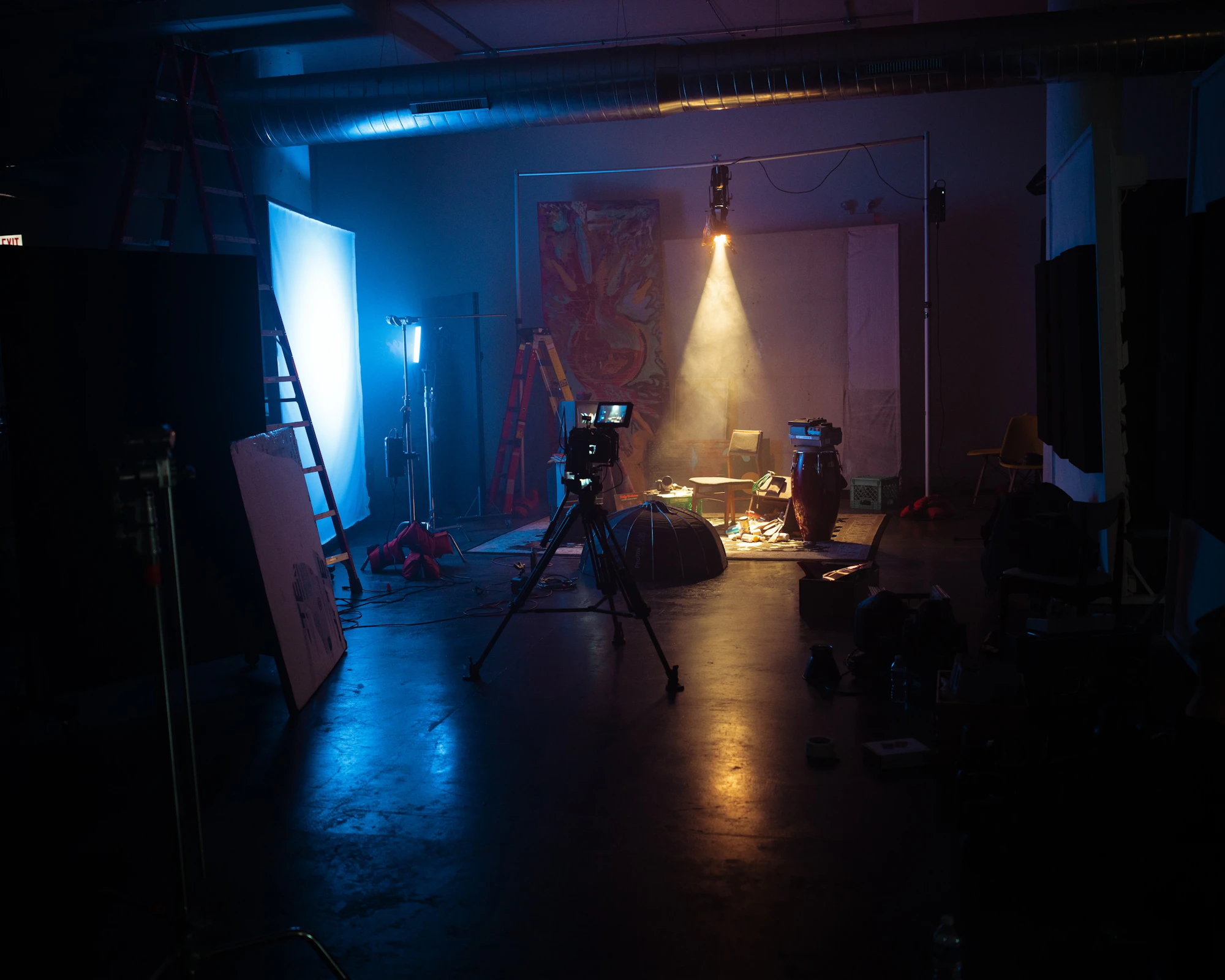 Dark set with a camera on a tripod and a spotlight