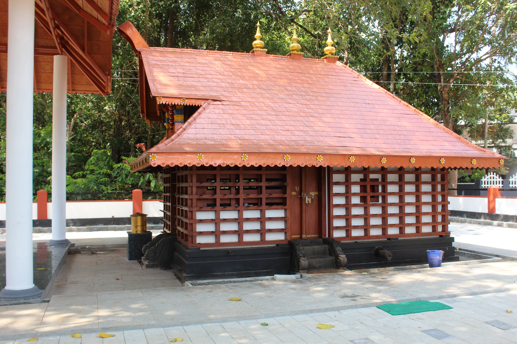 Small wooden shrine-like building with a copper-red roof